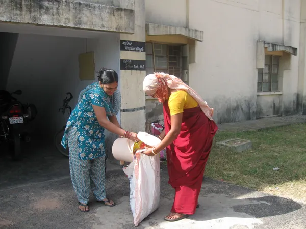 women pouring something from a bucket into a sack